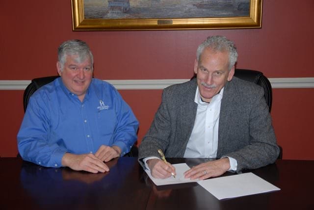 American Queen Steamboat Company Chairman and CEO John Waggoner (right) and HMS Global Maritime In-House Legal Counsel Bob Herre (Left) sign documents officially closing the purchase of the American Empress from the US Maritime Administration. Photo courtesy of American Queen Steamboat Company
