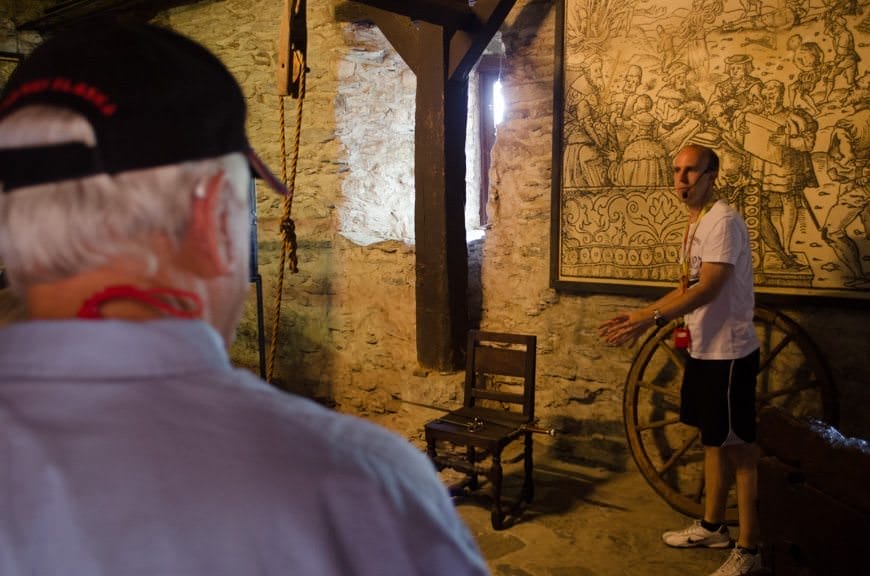 Here, our guide demonstrates how various instruments of torture were used. One involved feathers and tickling. No kidding! Photo © 2015 Aaron Saunders