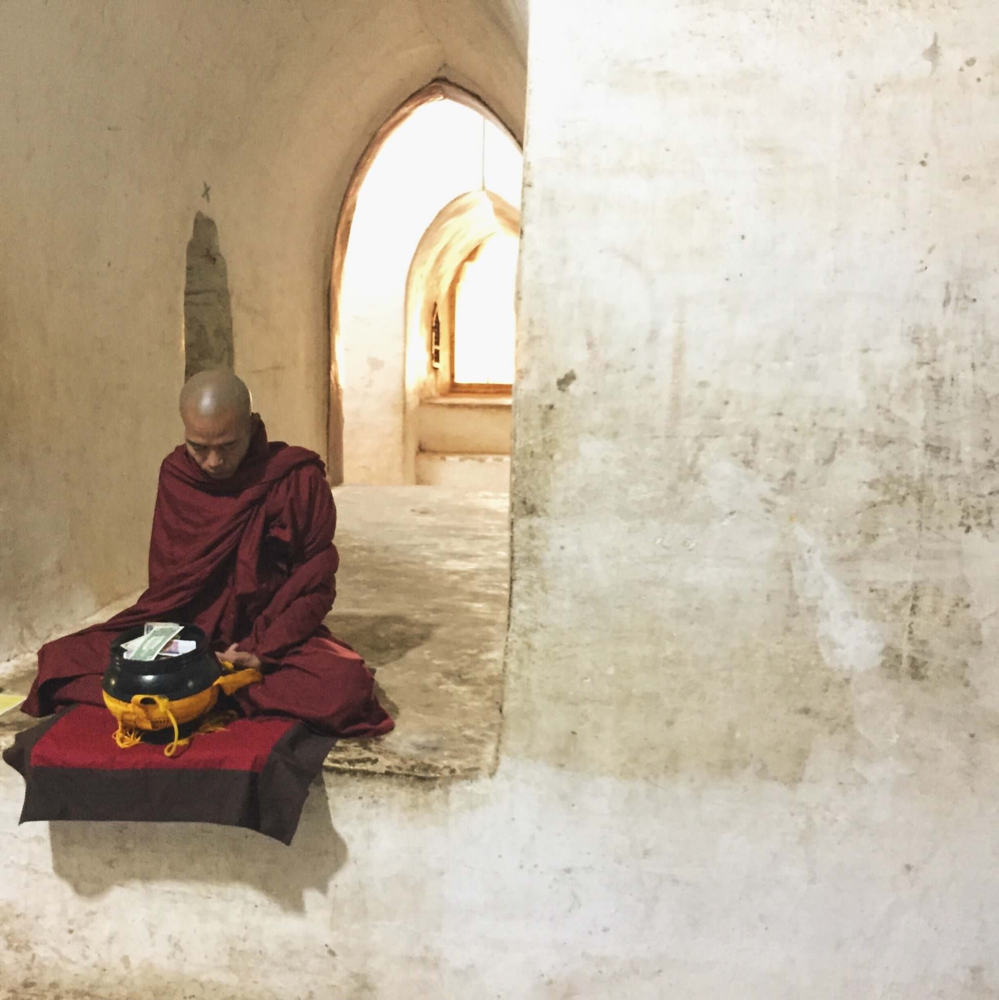 A Buddhist monk prays inside the hallways of the temple, accepting offerings of money or food. © 2015 Gail Jessen