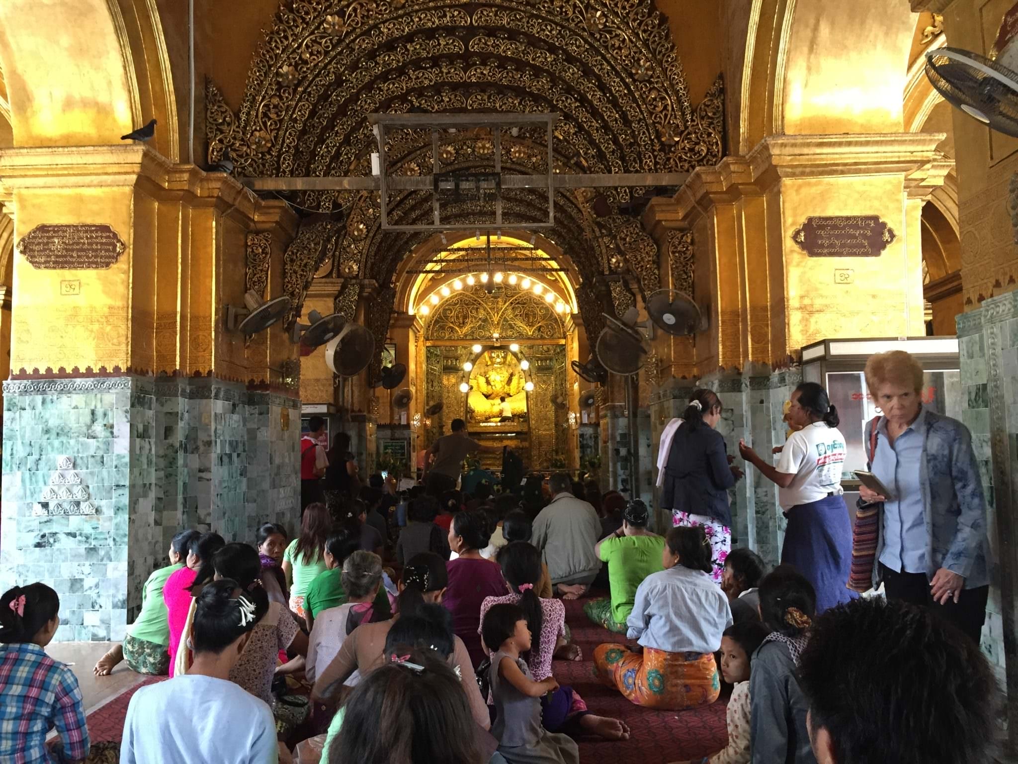 Women are not allowed to enter the chamber housing the Buddha. Men may act as a proxy for offerings of gold leaf from the women in their lives. © 2015 Gail Jessen