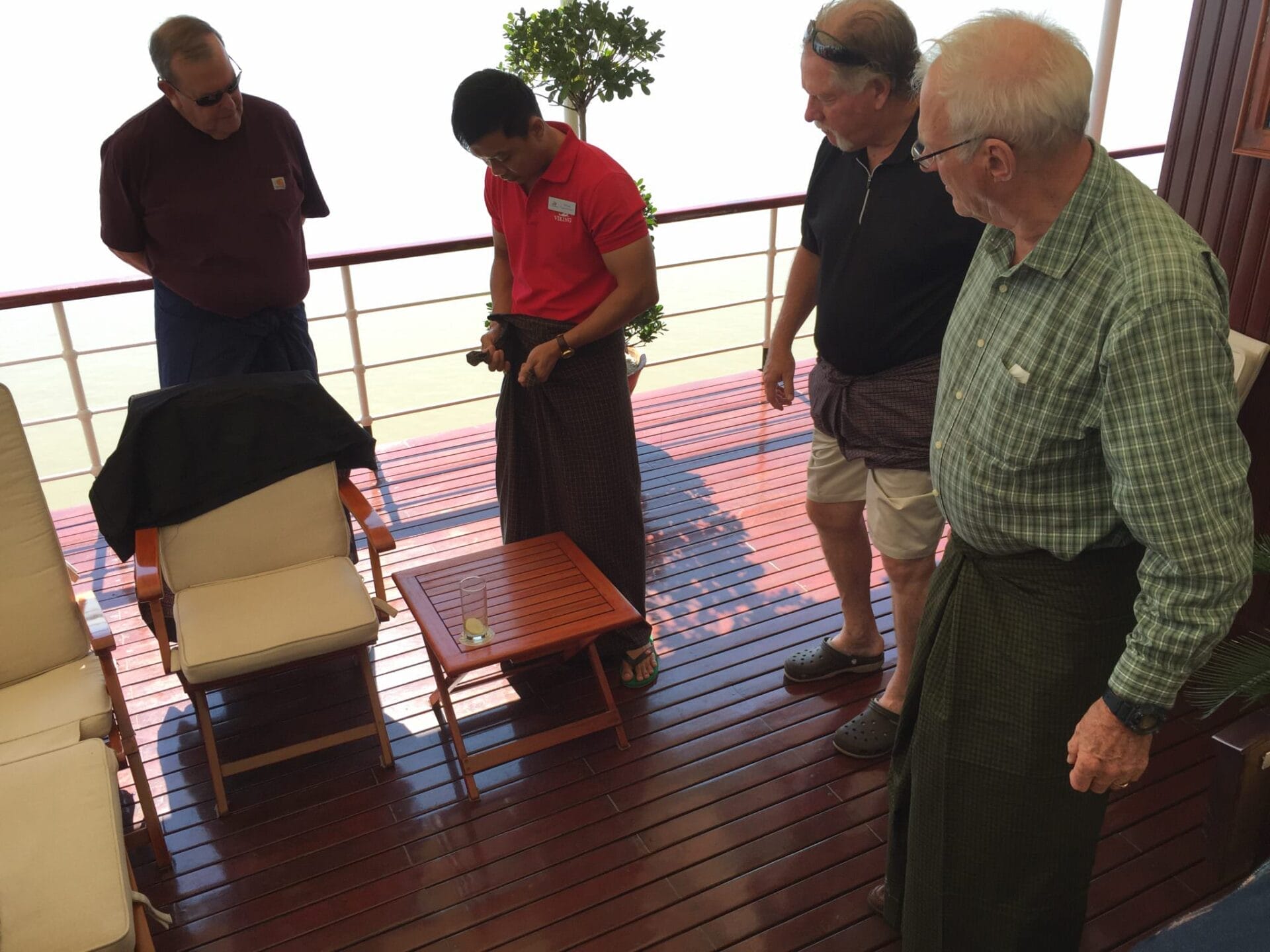 Fellow passengers attempt to wrap and tie their longhis, with one guest going full girding (used when playing sports). Most of the men found them very comfortable and two men wore them to dinner on the ship that night. © 2015 Gail Jessen