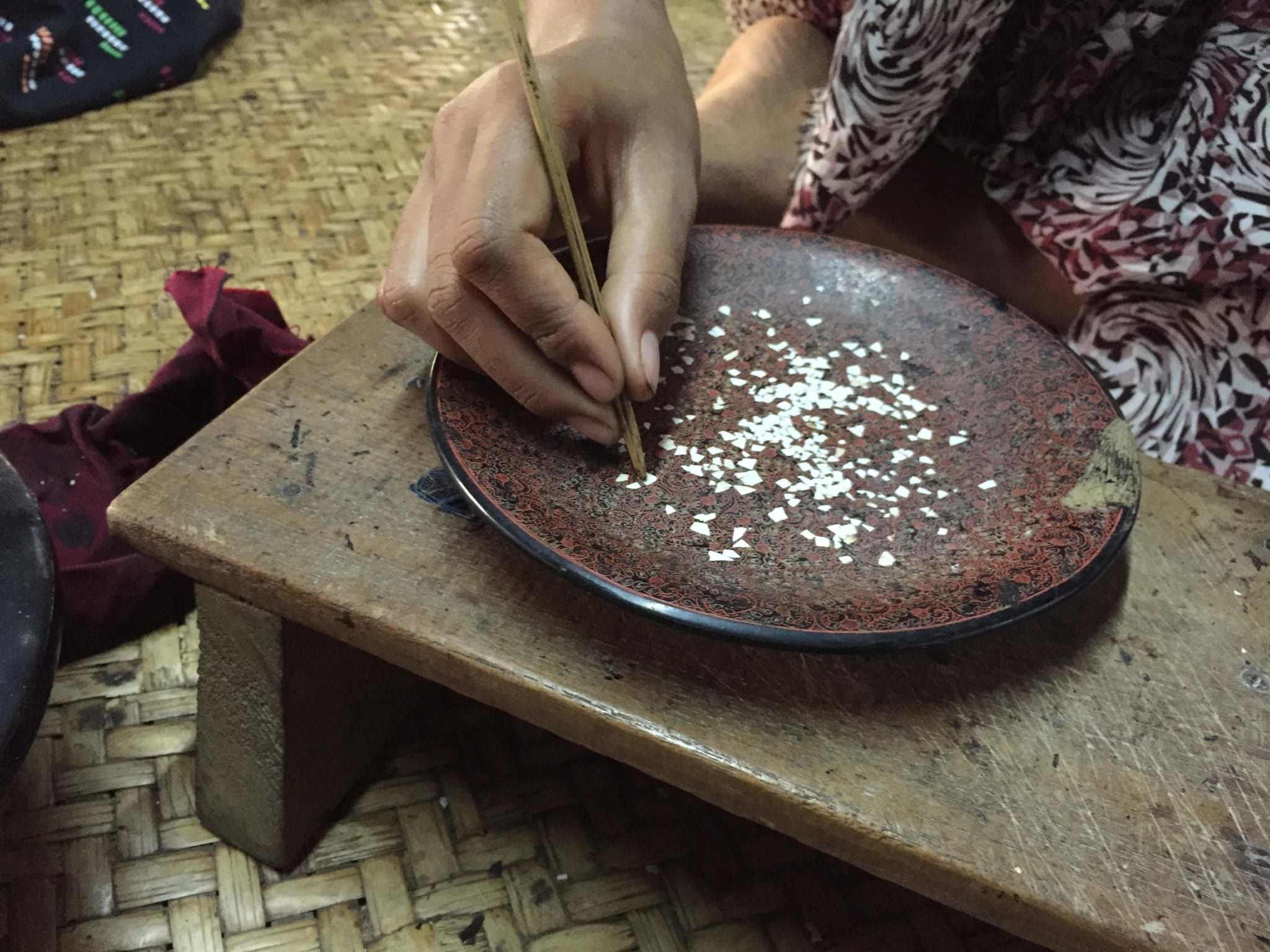 Egg shells are smashed and applied one tiny broken piece at at time on a large bowl, covering the entire surface. © 2015 Gail Jessen