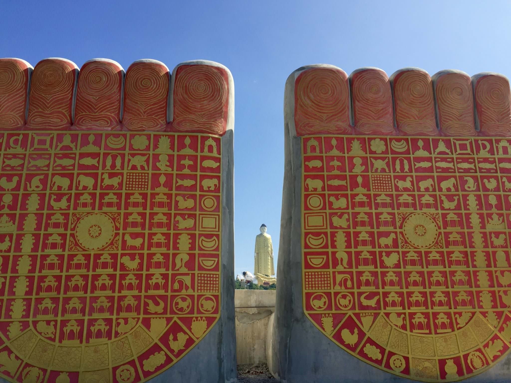 In the foreground are the feet of the Buddha model, displaying the story of Buddha's reincarnation. In the background are the gigantic Buddhas. © 2015 Gail Jessen